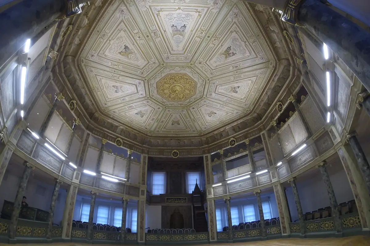 The painted octagonal ceiling of a ceremony hall with a gilded central medallion and high windows around the walls.